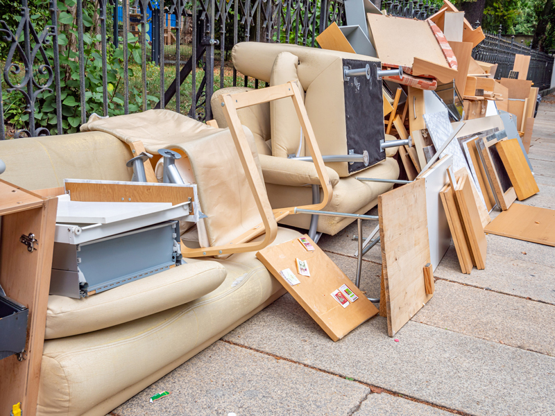 Old couches, chairs and wood panels piled on a sidewalk for junk removal