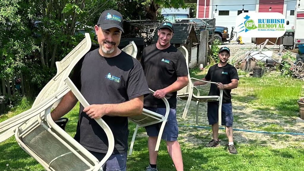 Three Big Phil's Rubbish Removal crew members carrying old patio chairs out of a yard